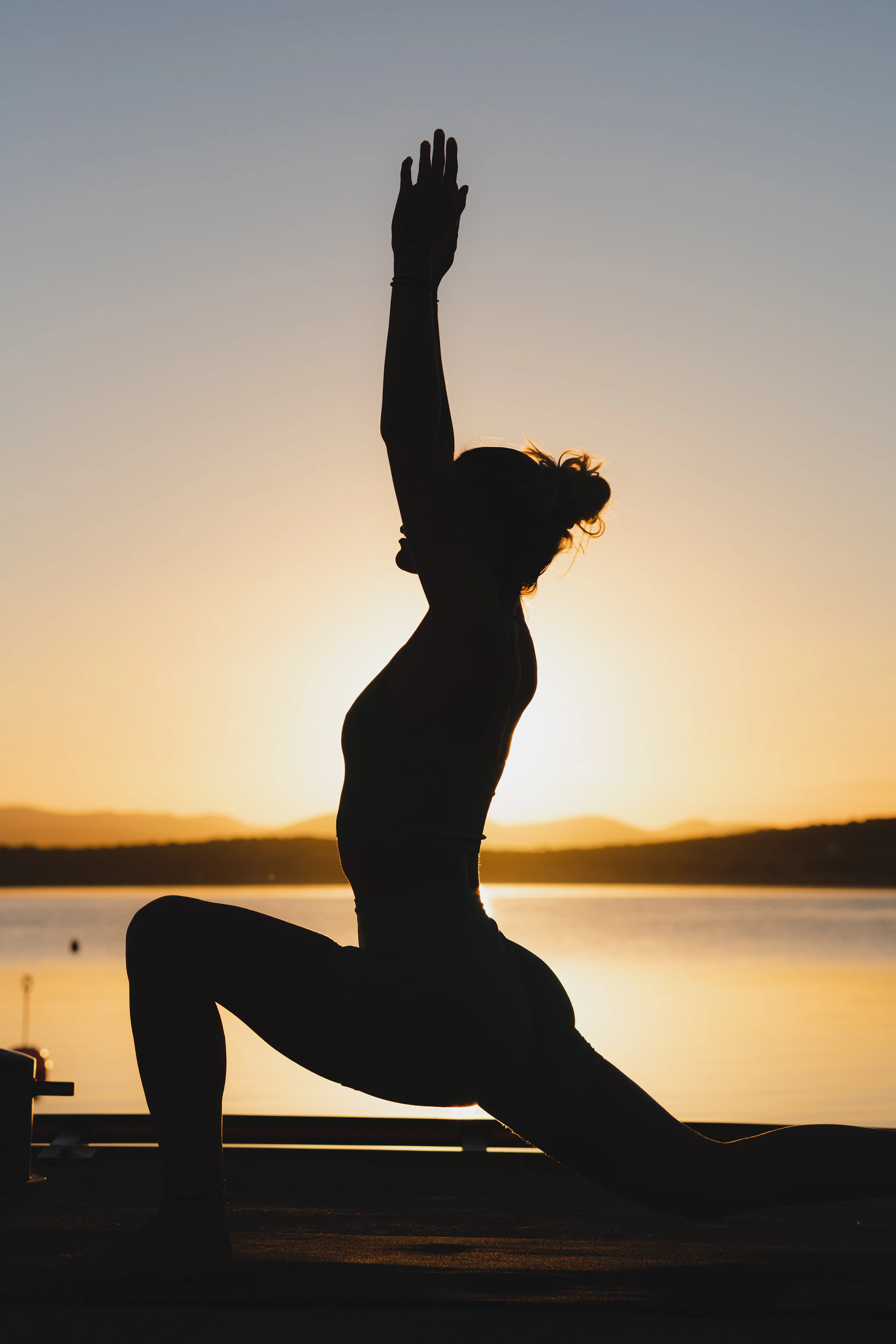 Mujer practicando una postura de yoga frente al mar